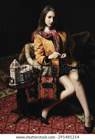 Indoor portrait of young beautiful european brunette model sits dressed vintage way in retro interior