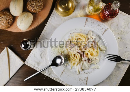 Carbonara pasta spaghetti with cream sauce and ham on white plate. Styled dish for luxury restaurant menu