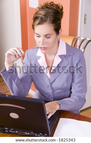 A young woman in business suit with glasses working from home