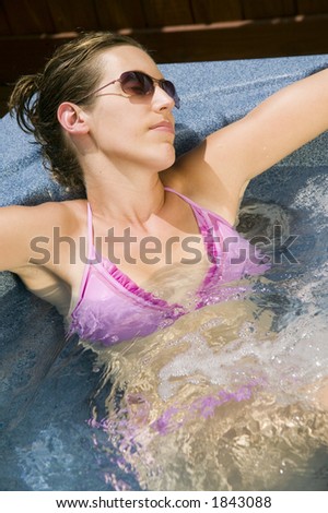 An attractive young woman spends a summers afternoon relaxing in the Jacuzzi