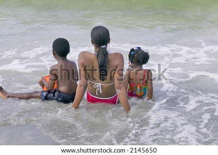 African american mother and two children enjoy a day relaxing and playing at the beach