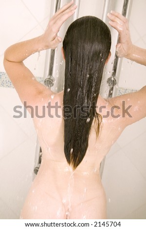 attractive young brunette woman washes her hair in the shower