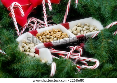 Candy cane serving dish filled with peanuts and pistachio nuts surrounded by candy canes and a pine wreath