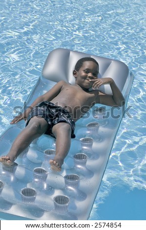 A young african american boy enjoys a day playing in the swimming pool