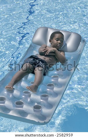 A young african american boy enjoys a day playing in the swimming pool
