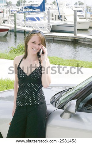 Attractive young red head business woman stays in touch on the go with the latest technology in cell phones and laptops
