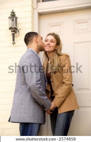 Young attractive couple saying good bye outside the front door