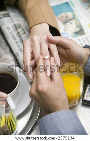young man proposes to a young woman at an outside cafe over brunch