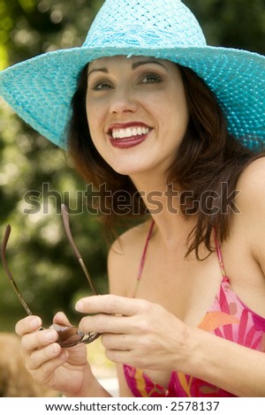Young attractive woman in blue summer hat and pink beach wear.