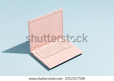 Retro pink laptop on a pastel blue background. Technology. Creativity and minimalism.