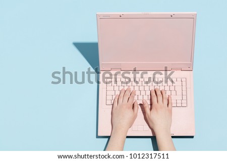 Woman\'s hands typing on a pastel pink keyboard of retro laptop. Work and technology.