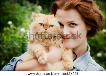 Young woman with Persian cat playing. Outdoors portrait