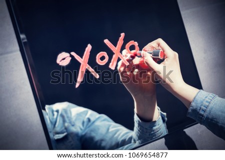 Woman writing xoxo on a mirror with red lipstick. Valentine\'s day. Love concept.