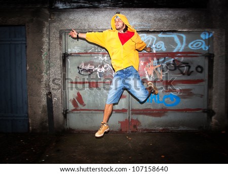 Young man jumping / dancing on grunge graffiti wall background