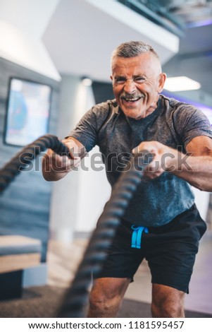 Senior man exercising with ropes at the gym. Physical activity and healthy lifestyle.