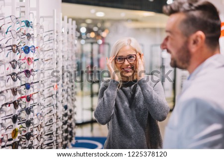 Optician and client choosing glasses together. Optical store, professional consulting.