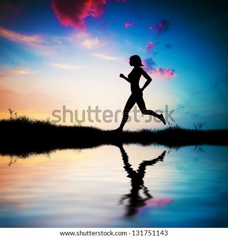 Silhouette of a fit woman running at sunset. Water reflection