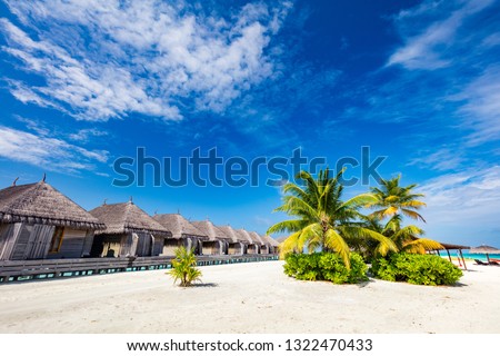 Tropical straw cabins on the tropical beach. Maldives, popular holiday destination. Travelling.