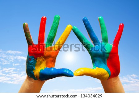 Painted hands, colorful fun. Creative, funny and artistic means happy! Blue sky background