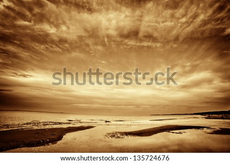 Fine art picture of sea, ocean at sunset. Dramatic sky, golden tint