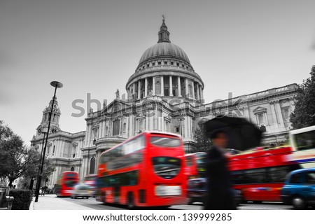 St Paul's Cathedral in London the UK Red buses in motion and man walking with umbrella St Paul's Cathedral in London the UK Red buses in motion and man walking with umbrella