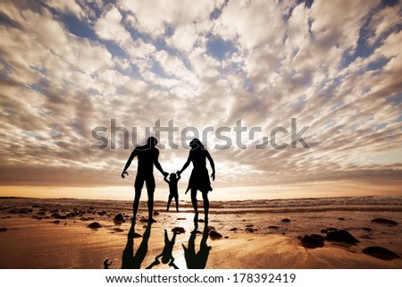 Happy Family Together Hand In Hand On The Beach At Sunset, Summer Time. Mother, Father And A Little Child