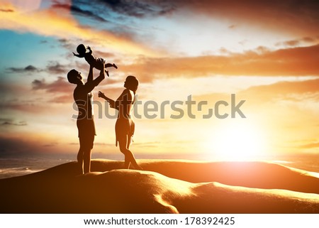 Happy family together, parents celebrating their little child by the seaside at sunset, summer time. Birth, mother, father concepts