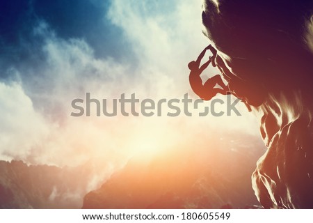 A silhouette of man climbing on rock, mountain at sunset. Adrenaline, strenght, ambition