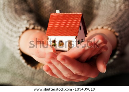 Woman holding a small new house in her hands. Real estate, mortgage, housing concepts etc.