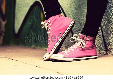 Close up of pink sneakers worn by a teenager. Grunge graffiti wall, concepts of teen rebel, problems of the youth, drugs, alcohol.