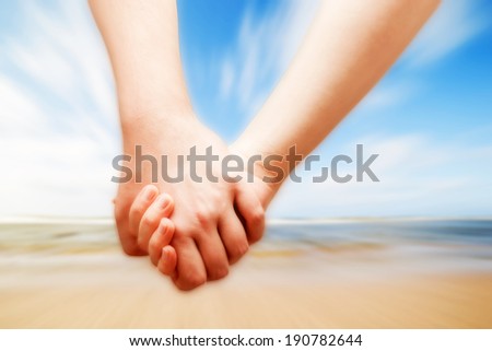 A couple in love hand in hand on the sunny beach. Vacation, romance, happiness