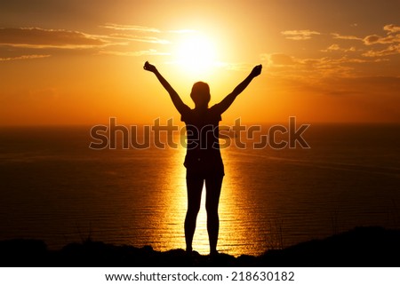 Happy woman on the rock with hands up. Winner, success, active, travel concepts.