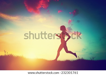 Silhouette of a fit woman running at sunset. Training, jogging, healthy lifestyle.