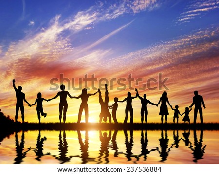 Happy group of diverse people, friends, family, team standing together holding hands and celebrating success. Water reflection, sunset sky