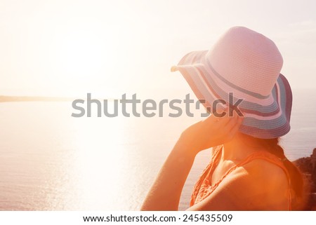 Happy woman in sun hat enjoying the sea view on Santorini, Greece. Aegean sea. Travel, tourist concepts