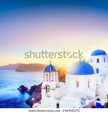 Oia town on Santorini Greece at sunset. Traditional and famous white houses and churches with blue domes over the Caldera, Aegean sea