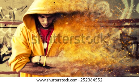 Young man portrait in hooded sweatshirt, jumper on grunge graffiti wall. Particles effect