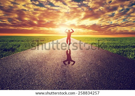 Happy man jumping on long straight road, way towards sunset sun. Travel, happiness, win, healthy lifestyle concepts.