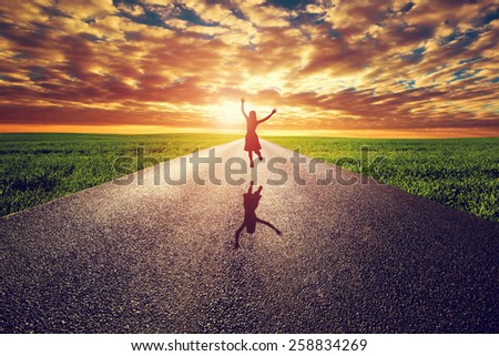 Happy woman jumping on long straight road, way towards sunset sun. Travel, happiness, win, healthy lifestyle concepts.