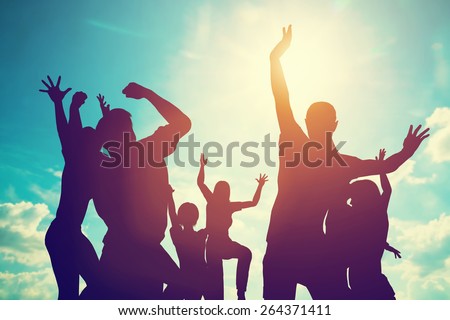 Happy friends, family jumping together in a circle having fun and expressing emotions of joy, freedom, success. Silhouettes on sunny sky