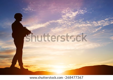 Armed soldier with rifle standing and looking on horizon. Silhouette at sunset. War, army, military, guard.