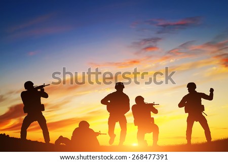 Soldiers in assault shooting with weapon, rifle at sunset. War, army, military.