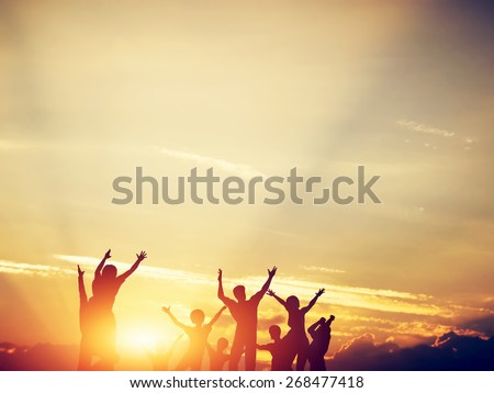 Happy friends, family jumping together in a circle having fun and expressing emotions of joy, freedom, success. Silhouettes on sunny sky