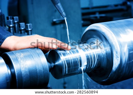 Worker measuring on industrial turning machine at work. Industry, precision.