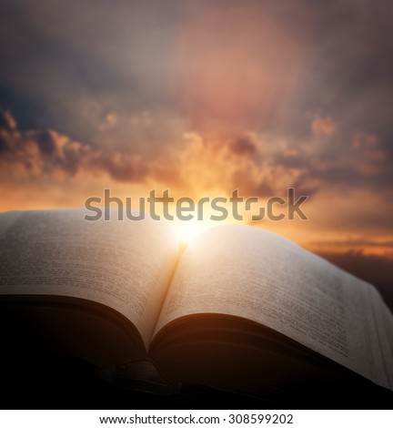 Open old book, light from the sunset sky, heaven. Fantasy, imagination, education, religion concept.