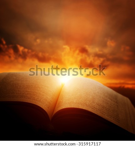 Open old book, light from the sunset sky, heaven. Fantasy, imagination, education, religion concept.