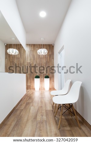 Modern waiting room, reception. Cozy minimalistic interior with seats, lights, mirror and parquet floor.