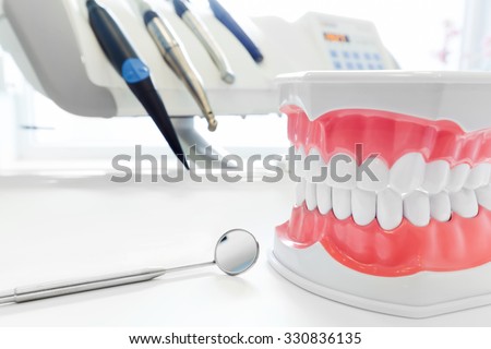 Clean teeth denture, dental jaw model, mirror and dentistry instruments in dentist\'s office.