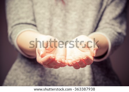 Light in young woman\'s hands. Palms in cupped shape. Concepts of sharing, giving, offering, taking care, protection.