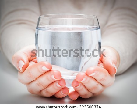 A glass of clean mineral water in woman\'s hands. Concept of environment protection, healthy drink.